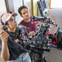 Two people starring intently at a screen of a camera while filming