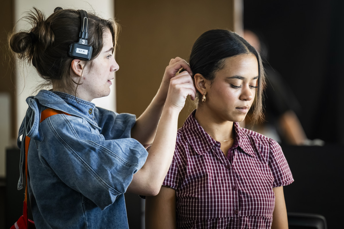 One person with headphones fixing the hair of another person