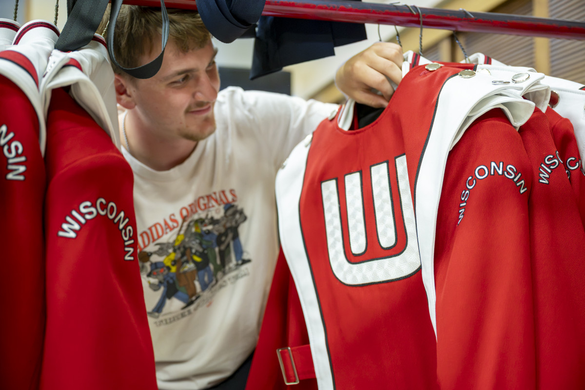 A band member inspects his uniform, featuring the UW Marching Band logo. 