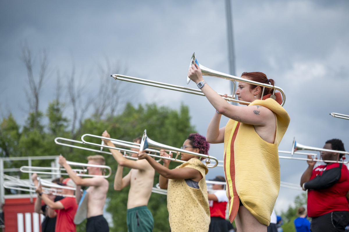 Band members dressed in playful costumes play their trombones.