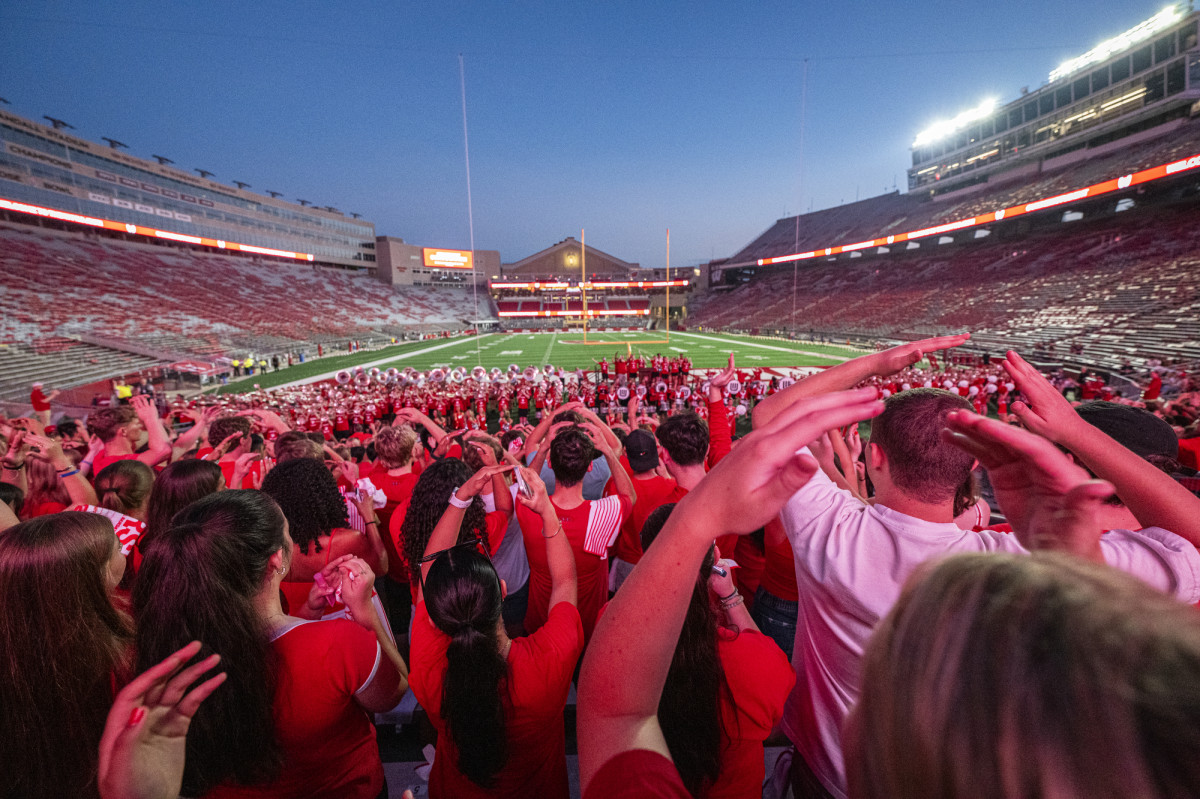 From behind, hundreds of UW students hold up their hands in an O formation as they learn a football chant.