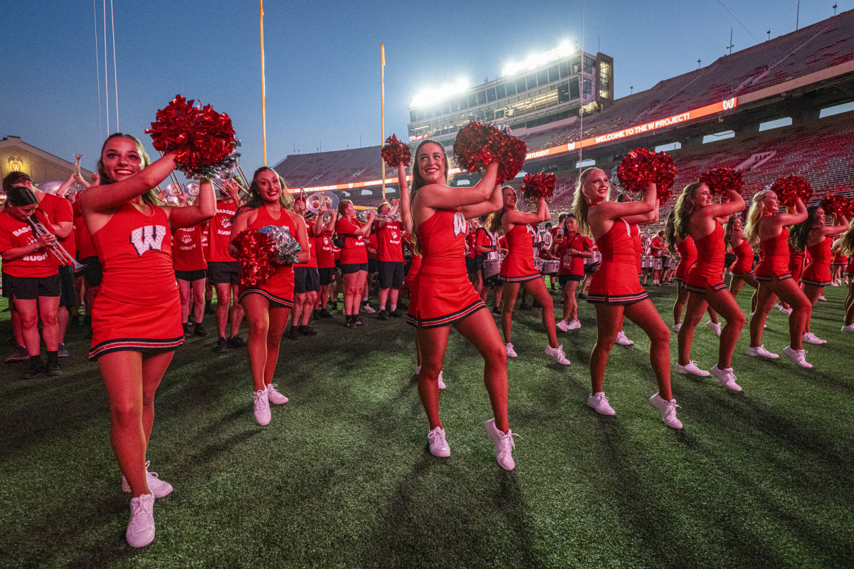 Members of the spirit squad, all wearing bright red uniforms with a W on the front, shake their pom-poms to cheer up the crowd.