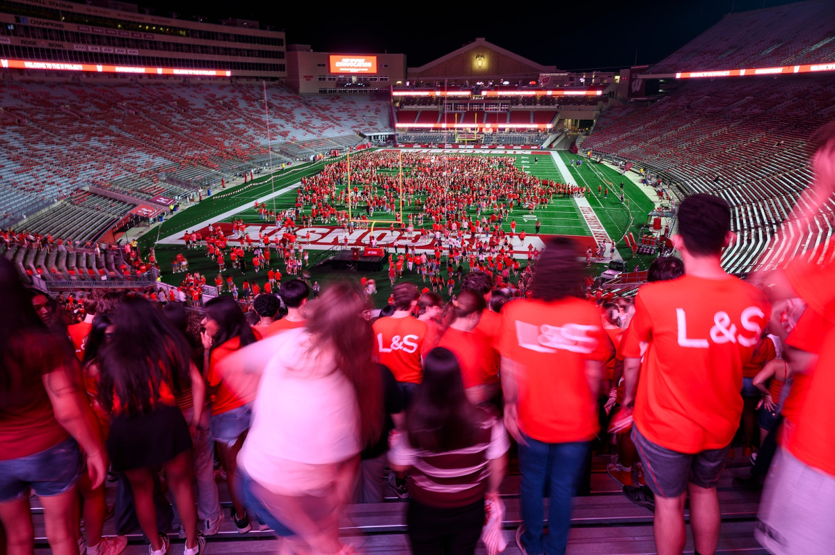 UW students watch from the stands as others start to form a W on the football field at Camp Randall Stadium.