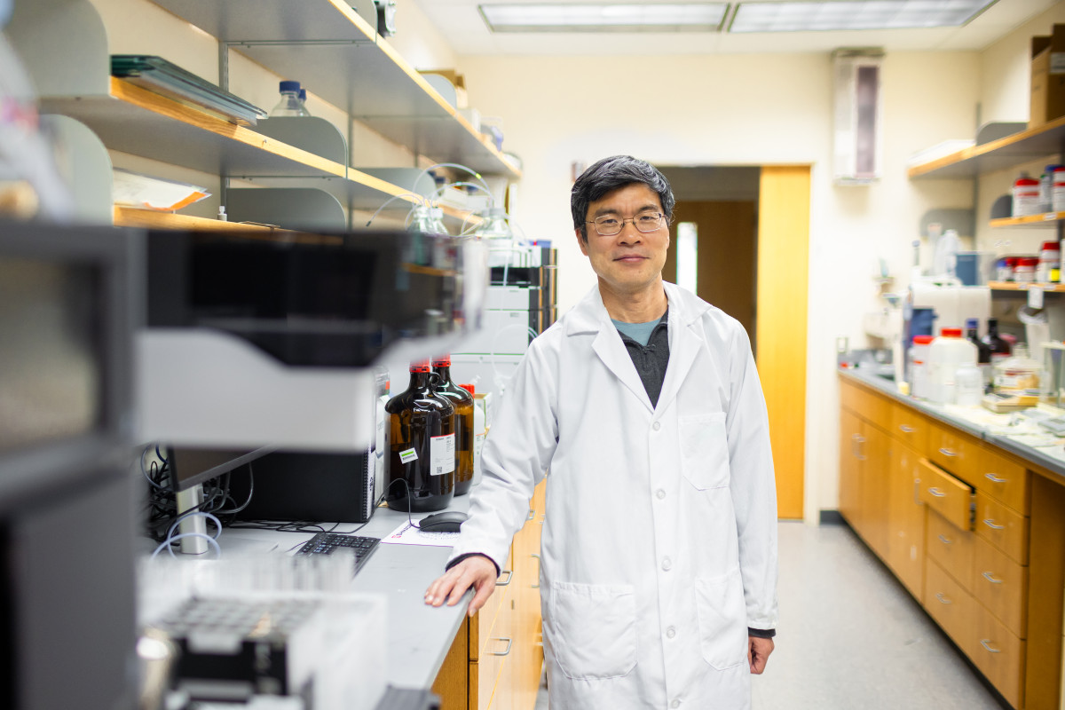 Wearing a white lab coat, Tang poses for a picture in his lab.