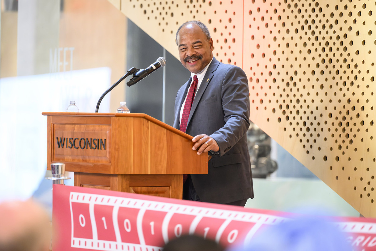 Eric Wilcots wearing a suit speaks at a podium