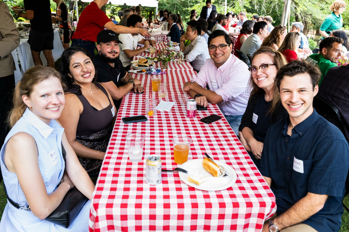 UW faculty sit around a red and white covered table and smile for a photo.