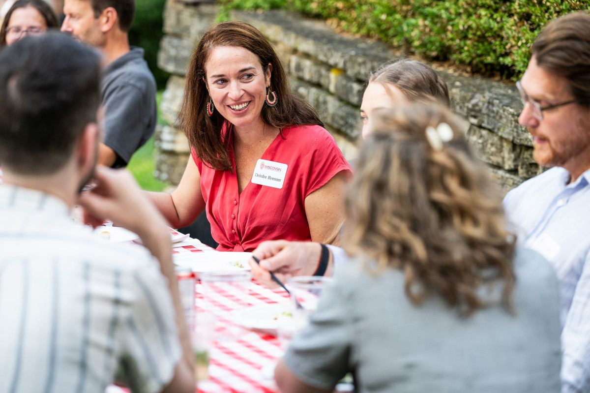 Brenner sits at a picnic table outdoors and speaks to other UW faculty sitting nearby.
