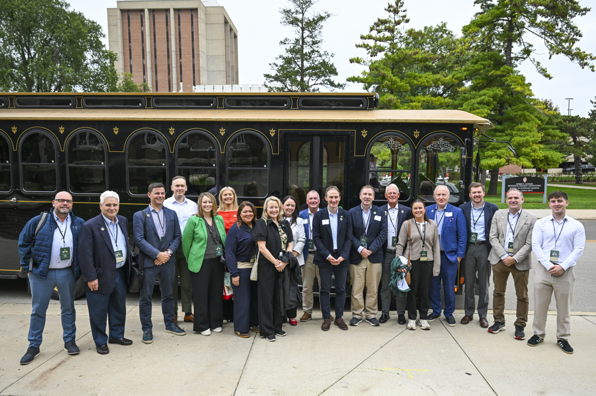 A large delegation in business attire stands in front of a trolley. 