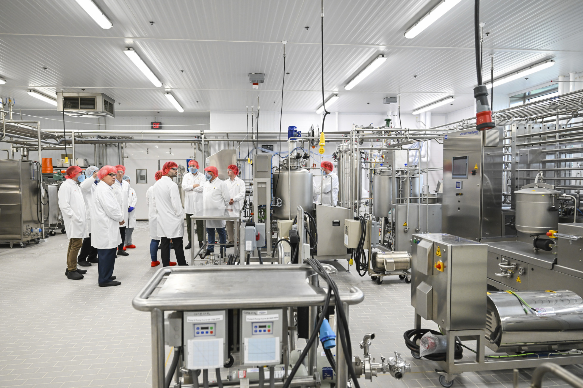 Visitors wearing safety gear tour the Center for Dairy Research, surrounded by equipment.