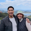 Student Marlee Rae Lee (right) pictured with her husband Meng Hsuan outdoors with hills and a large body of water in the background.