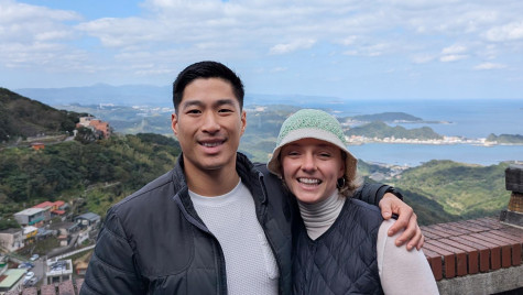 Student Marlee Rae Lee (right) pictured with her husband Meng Hsuan outdoors with hills and a large body of water in the background
