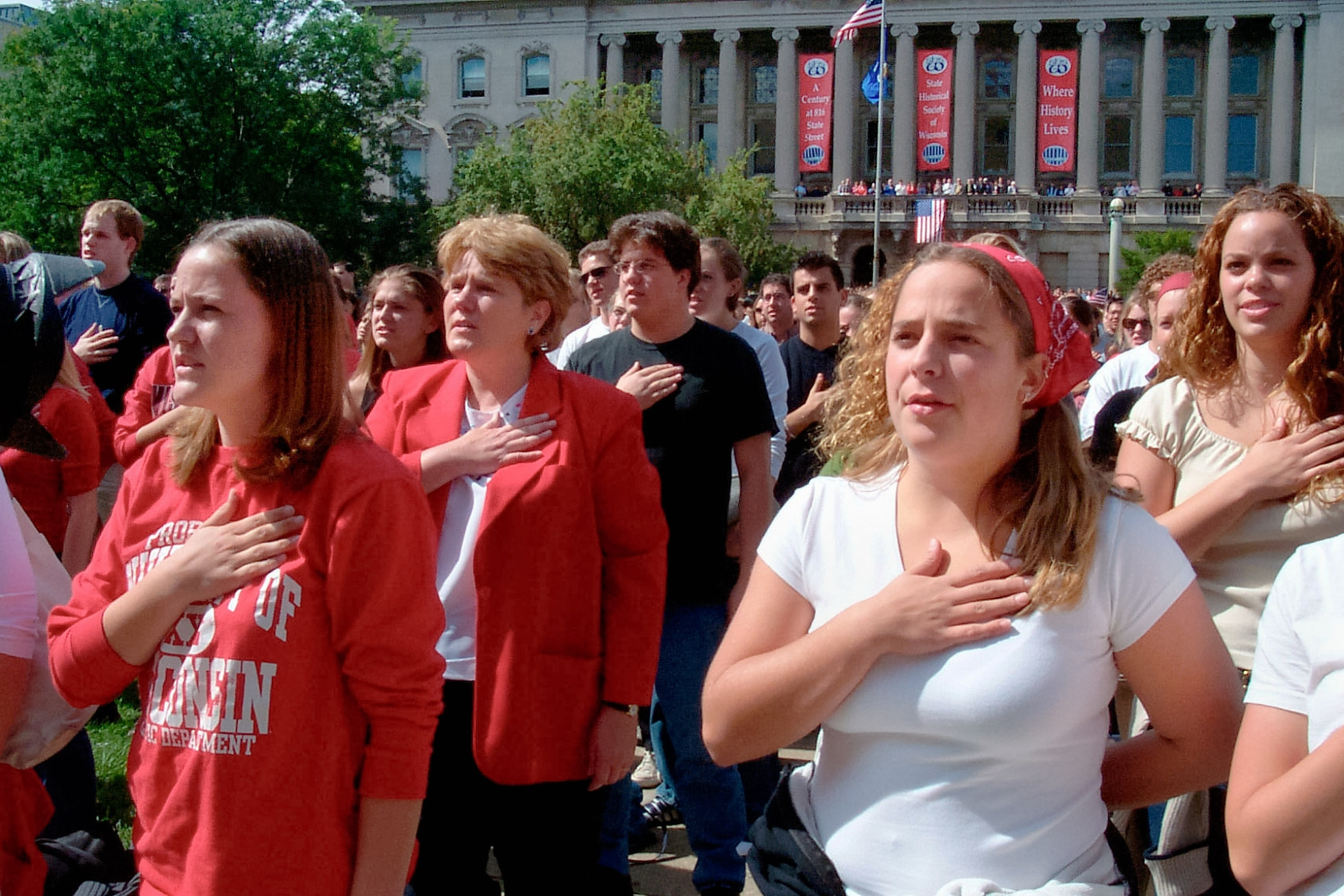 People stand and hold their hands over their hearts while reciting the Pledge of Allegiance.