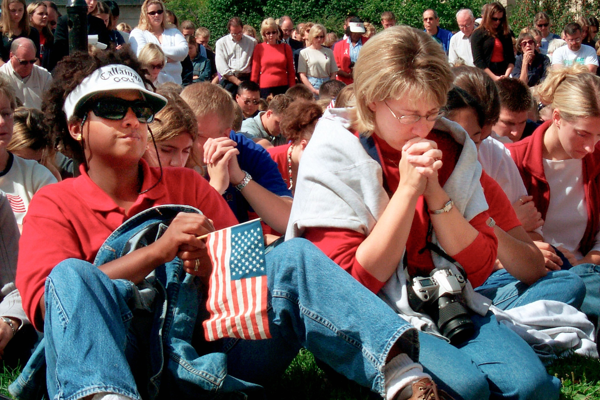People sit and hold their heads down during a moment of silence. 
