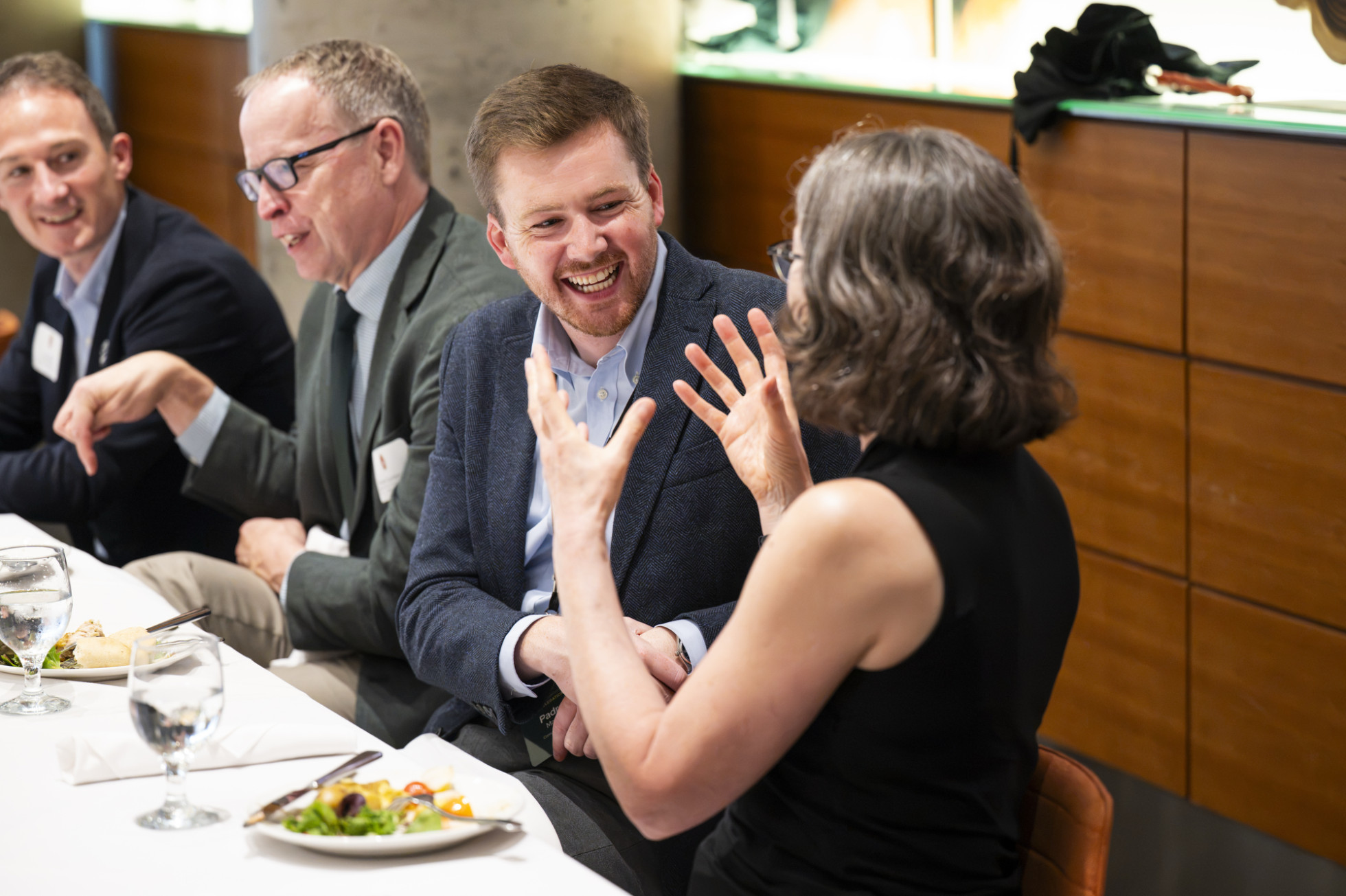 Pádraig Manning, smiling, and Frances Vavrus, gesturing with hands, speak to each other at a table during lunch.
