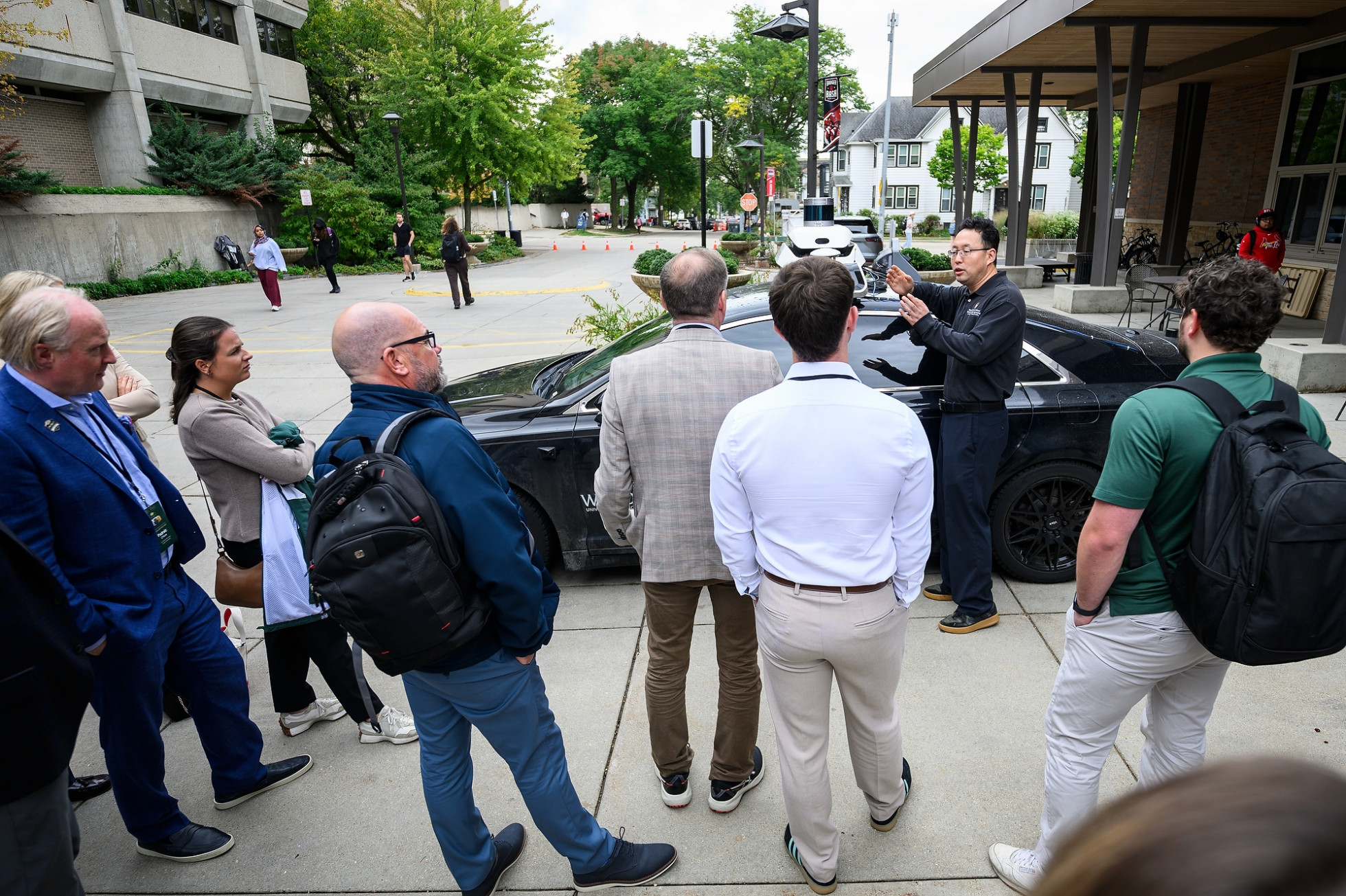 Professor Xiaopeng (Shaw) Li speaks to delegates in front of an autonomous vehicle.