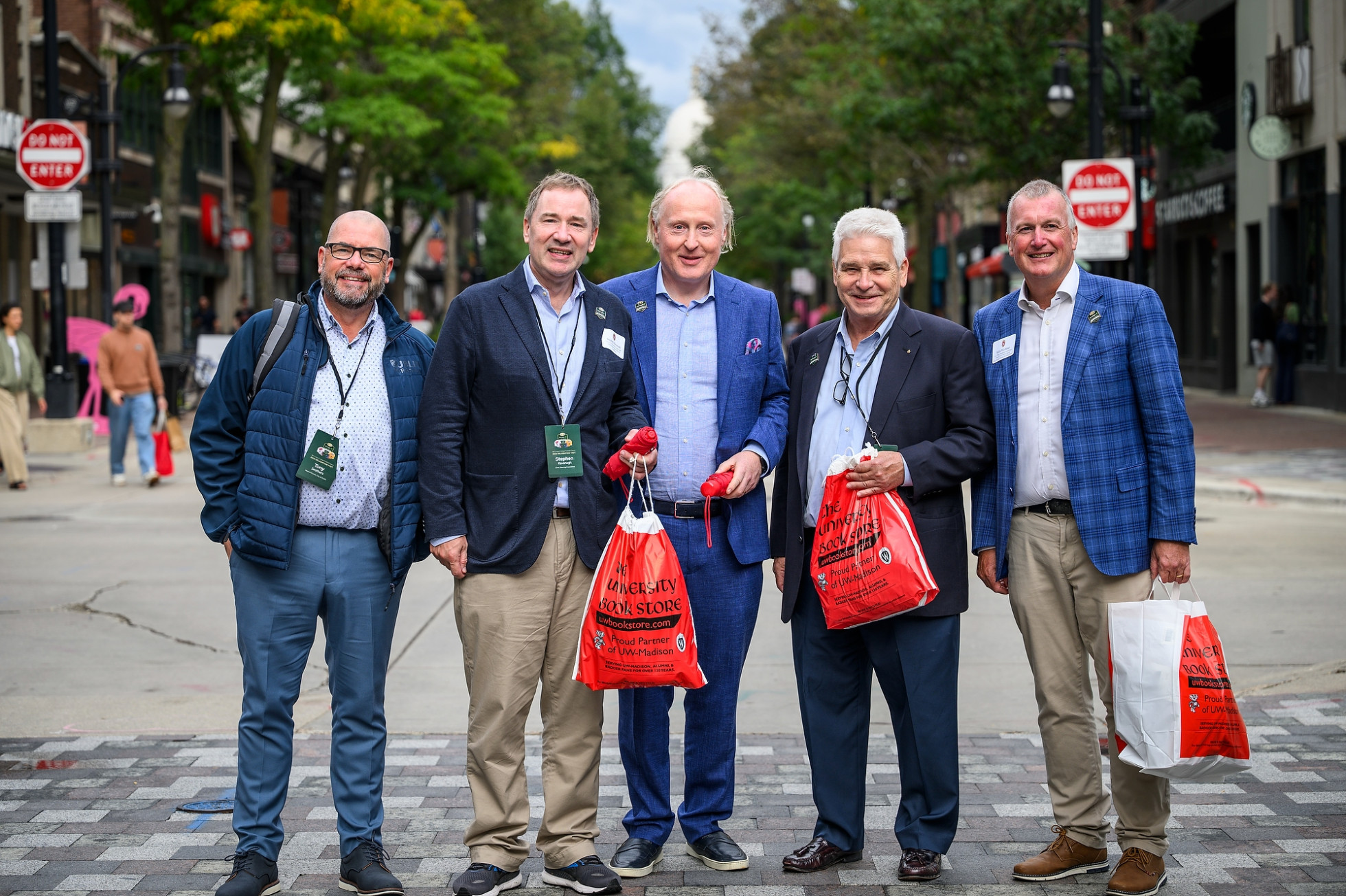 Visitors representing the Aer Lingus College Football Classic hold University Book Store bags and pose for a portrait in front of State Street.