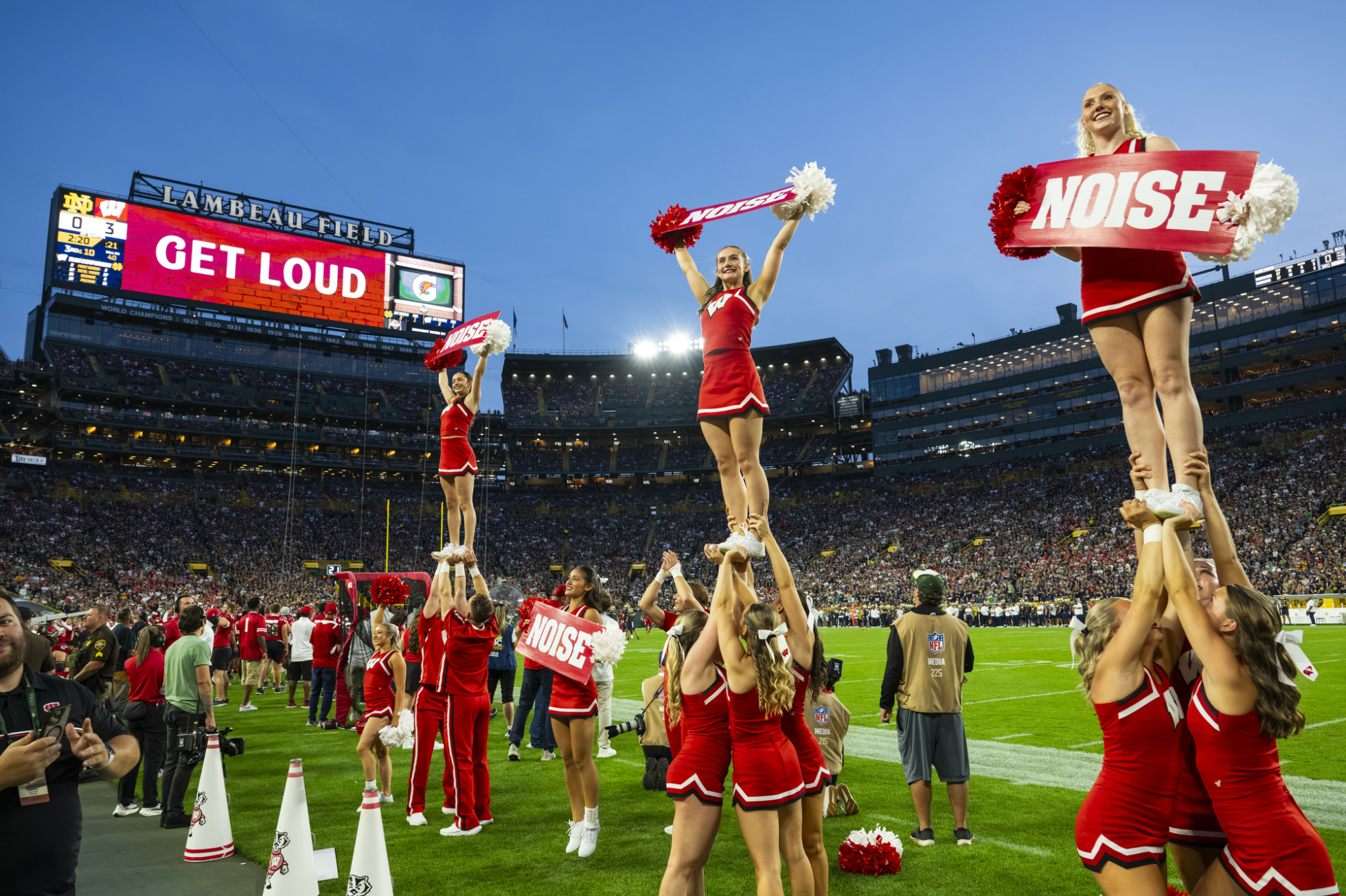 UW Spirit Squad Members pose and cheer on the sidelines of the field. 