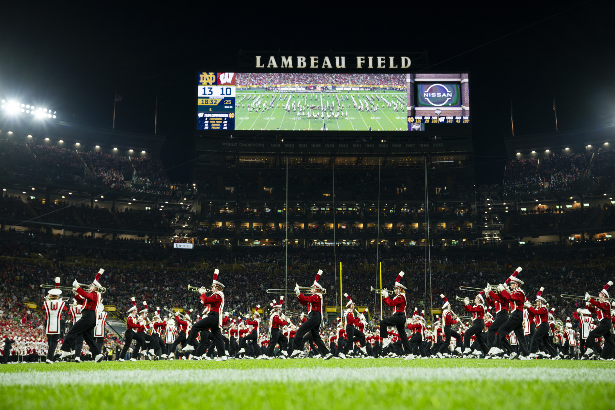 UW Marching Band members march and play instruments on the field.