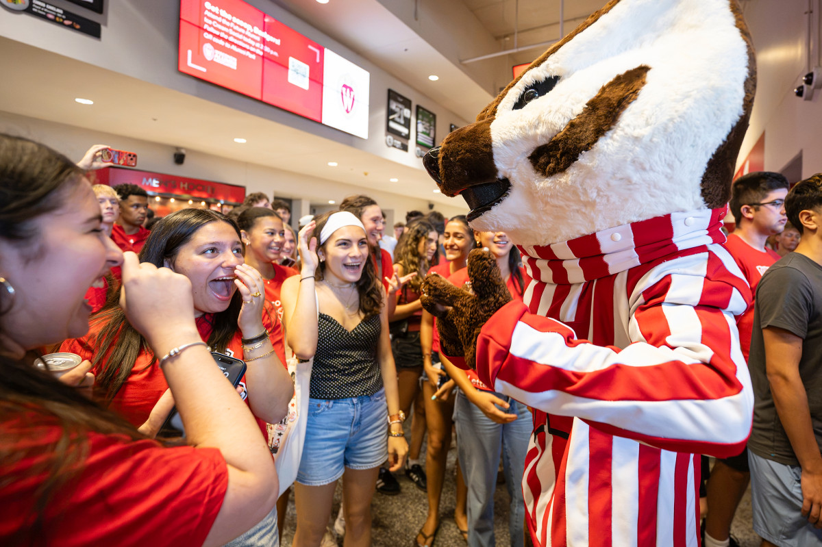 The Bucky Badger mascot interacts with delighted students in the Kohl Center concourse.