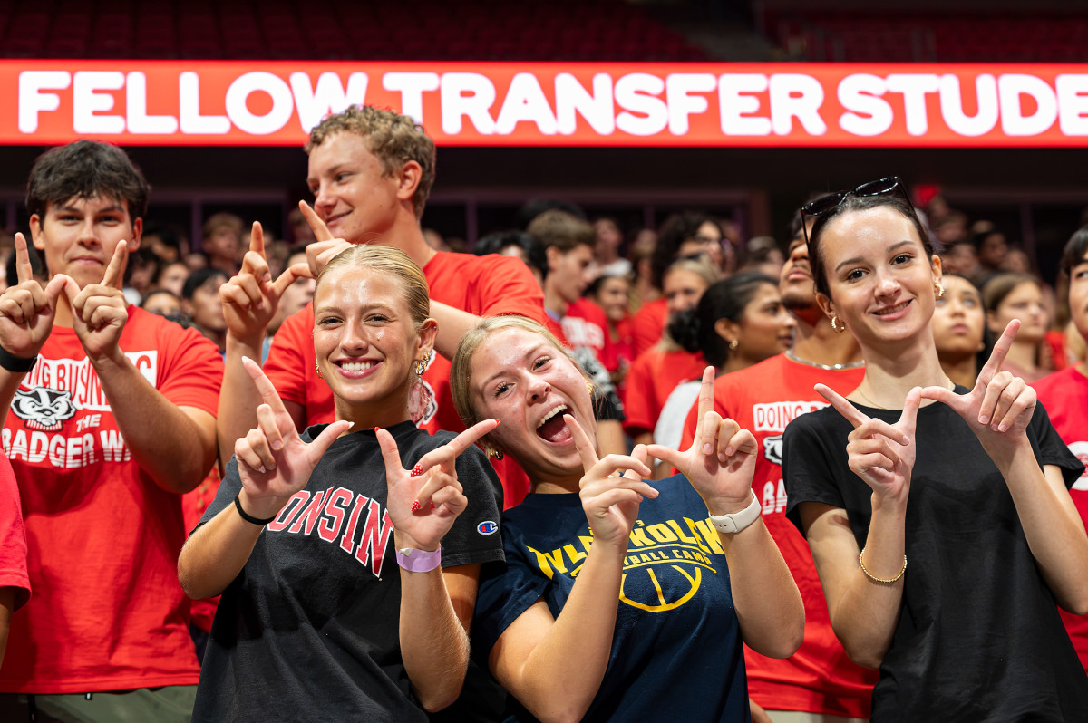 A group of students smile and make a W with their hands.