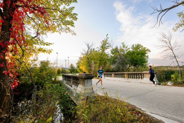 People jog over a short stone bridge on the UW-Madison campus.