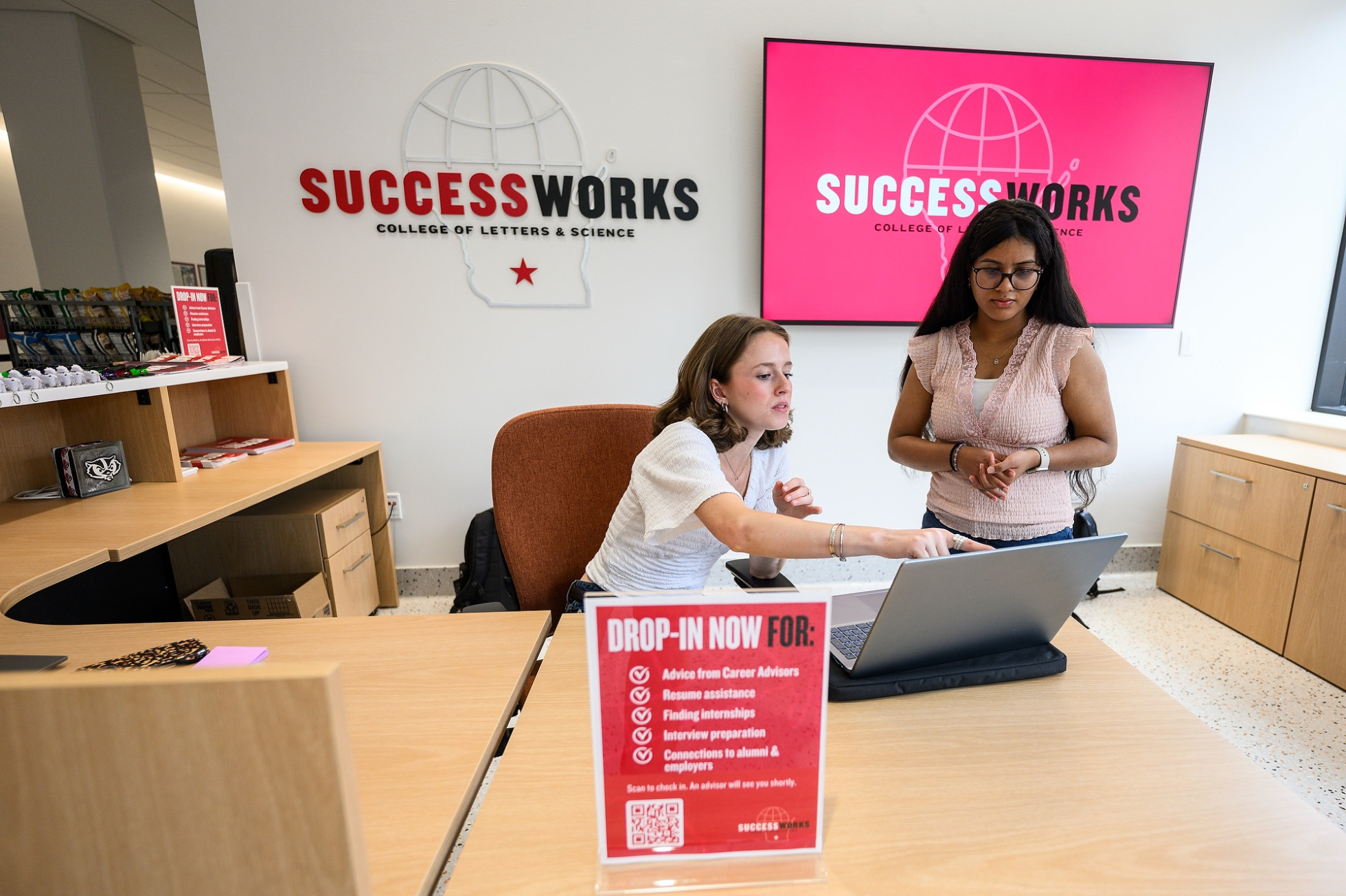 Two people look at a computer in the UW–Madison Success Works office. 