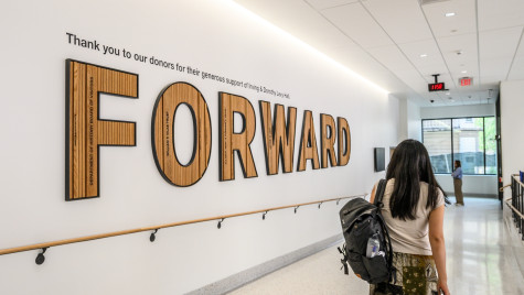 A student passes by a sign that says Forward in Levy Hall.