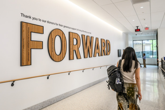 A student passes by a sign that says Forward in Levy Hall.