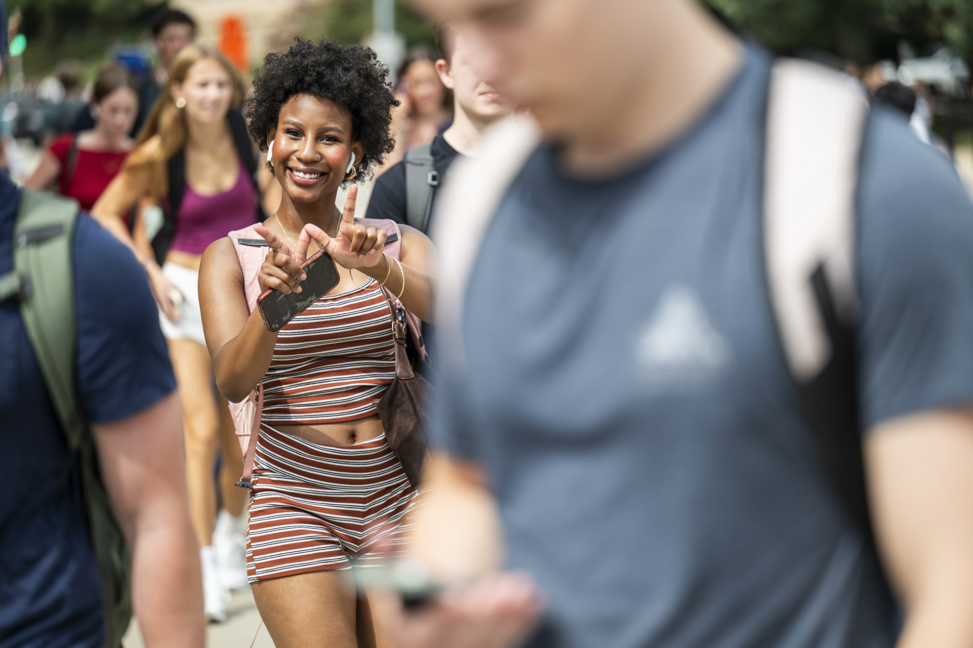 A student makes the W sign while walking to class. 