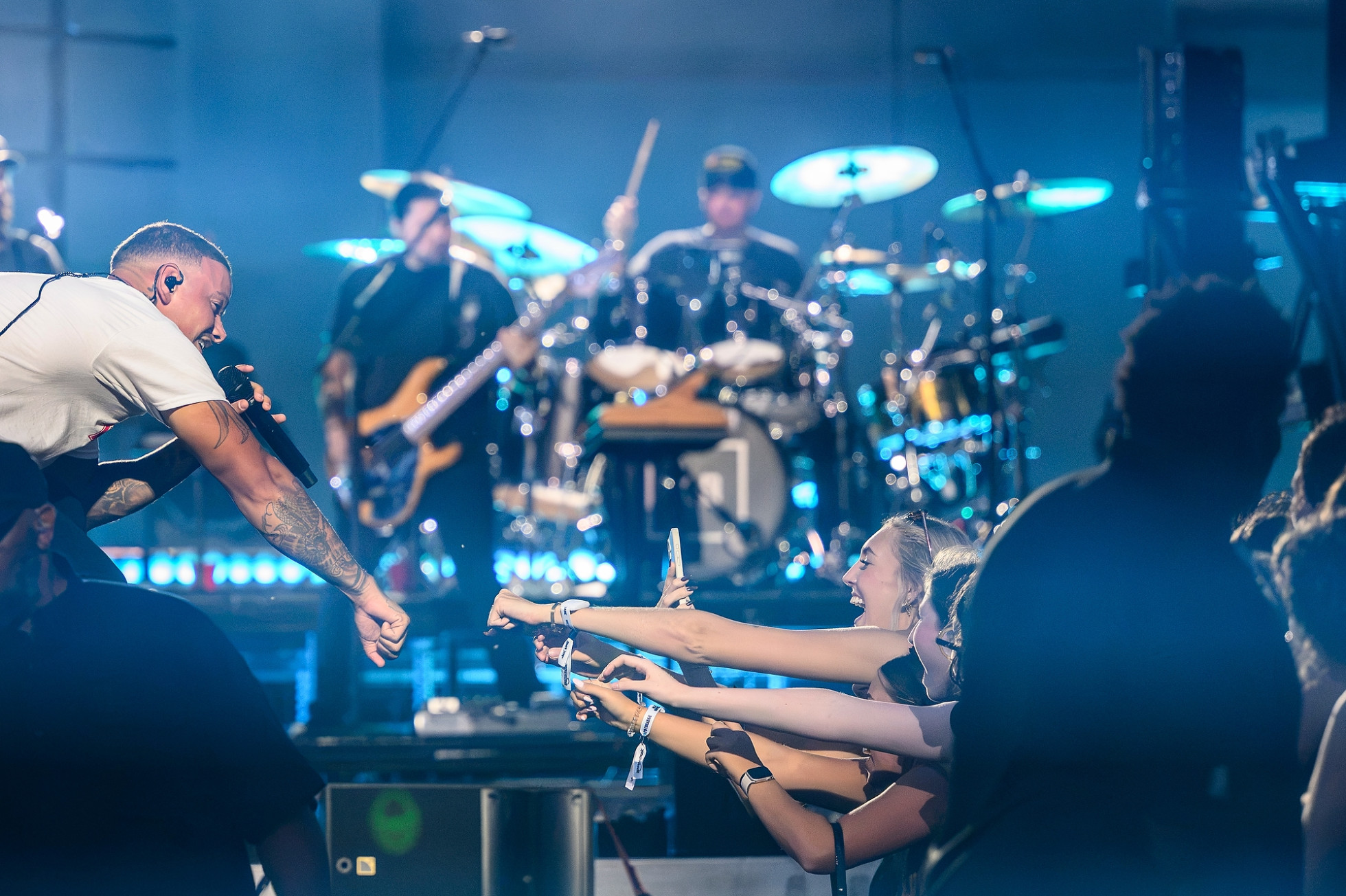 Kane Brown bumps fists with several fans in the front row of the stage.