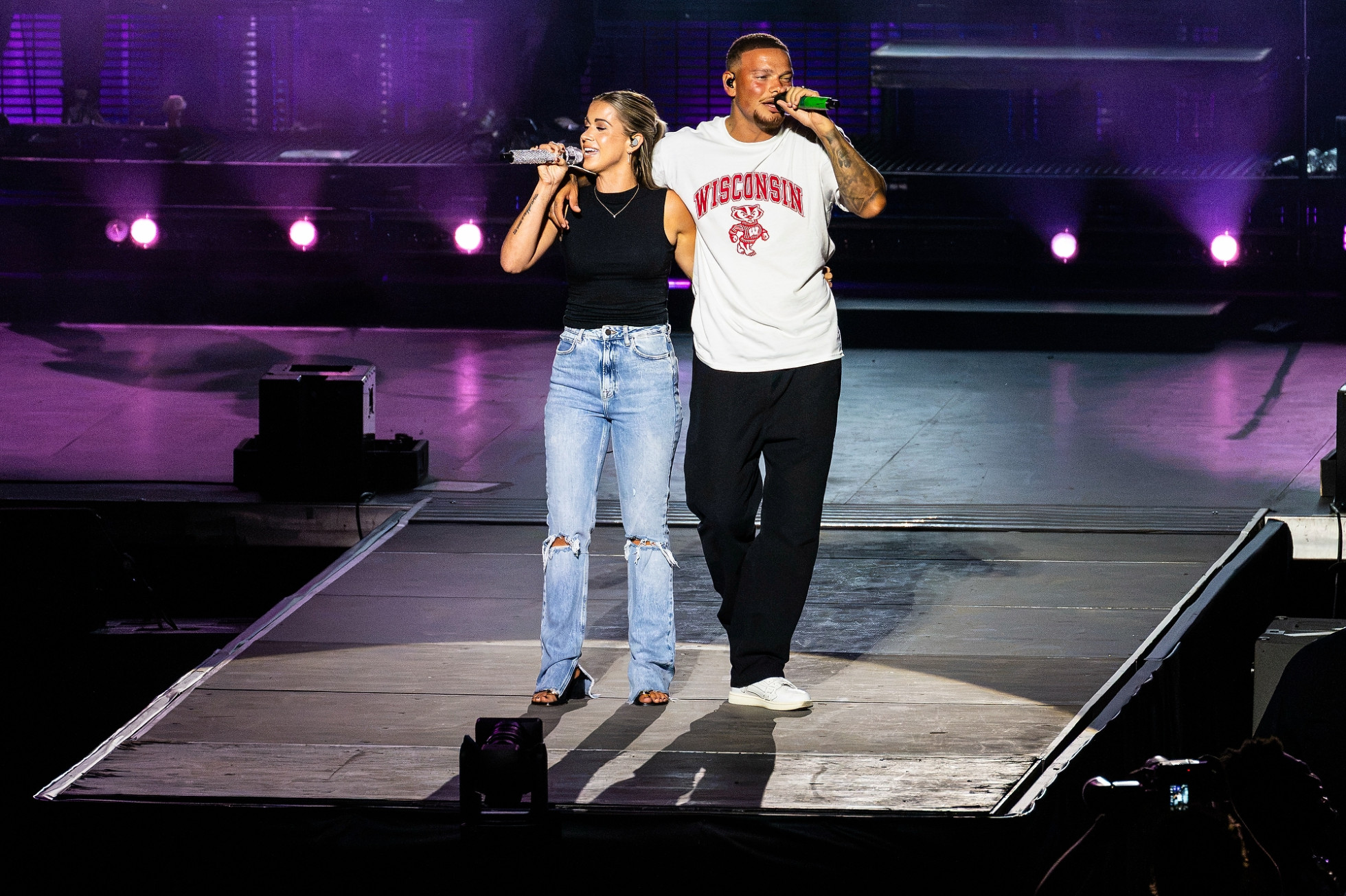Kane Brown and his wife, Katelyn Jae Brown, link arms and sing on stage. 