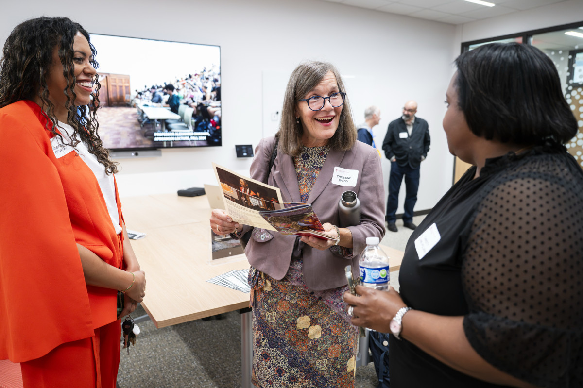 Three women talk in a classroom at Levy Hall.