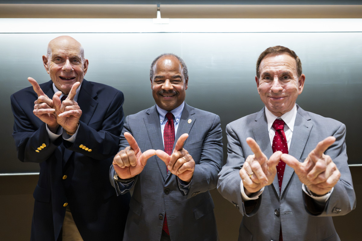 Marv Levy, interim Chancellor Eric Wilcots and Jeff Levy pose for a photo with their hands making a W sign.