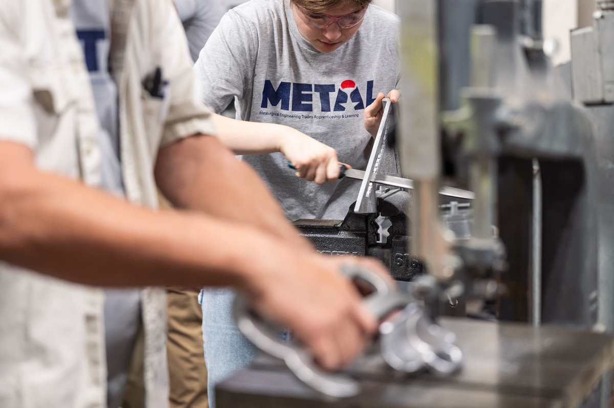 Two bootcamp students work with aluminum at their own metalworking stations.