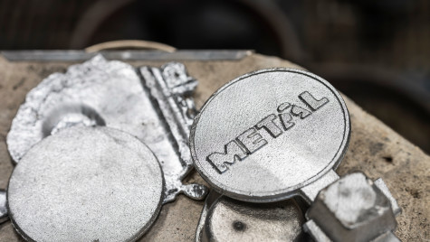 Silver aluminum medallions sit on a work station after being cast and cut.