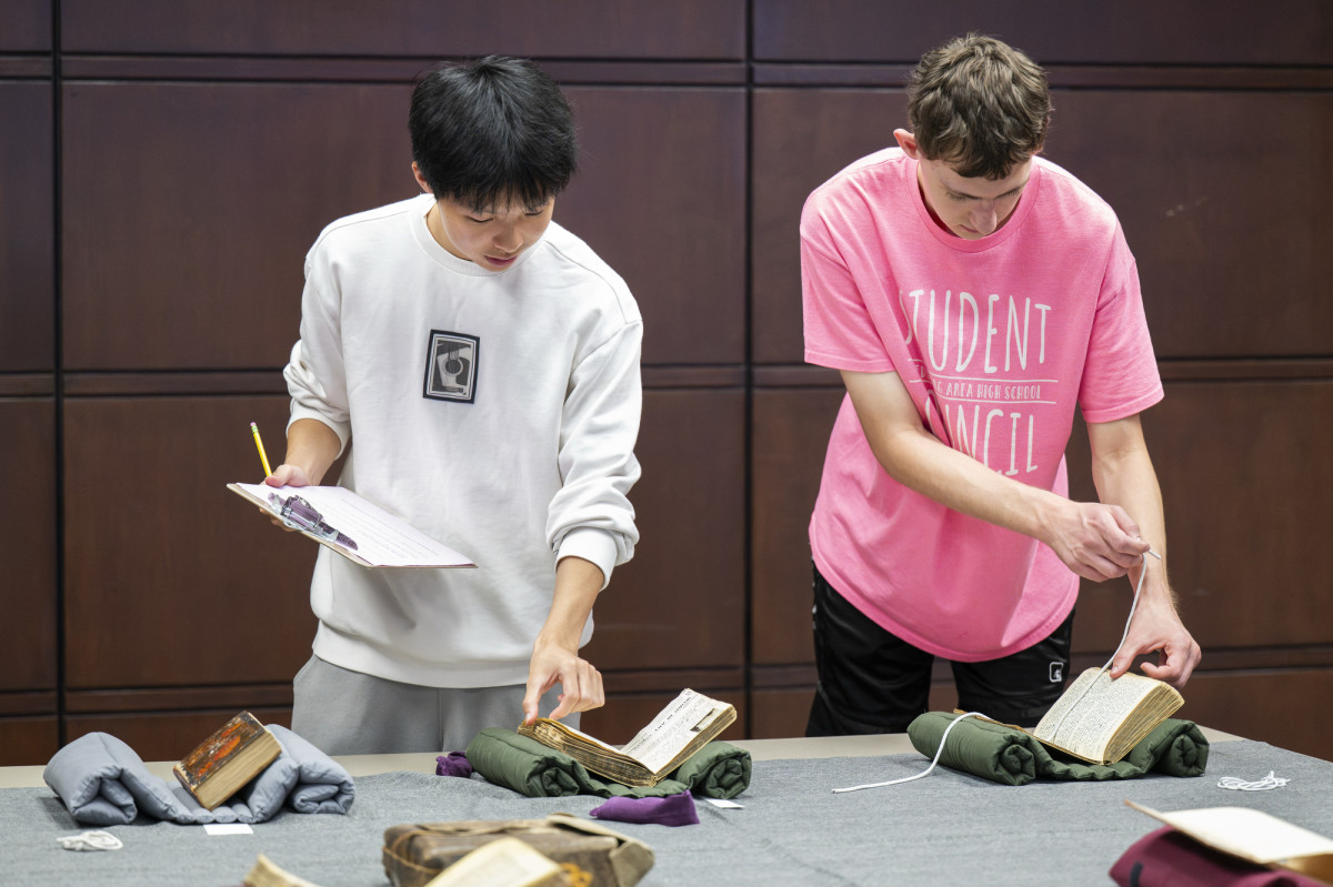 Two students page through rare books that are displayed on a table.