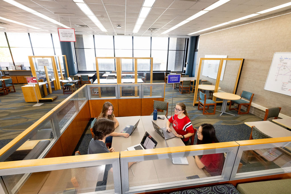Four students sit as a group and a table and engage in conversation.