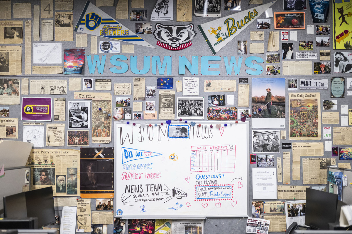 Wall of the WSUM news room showing a white board and clipped news stories