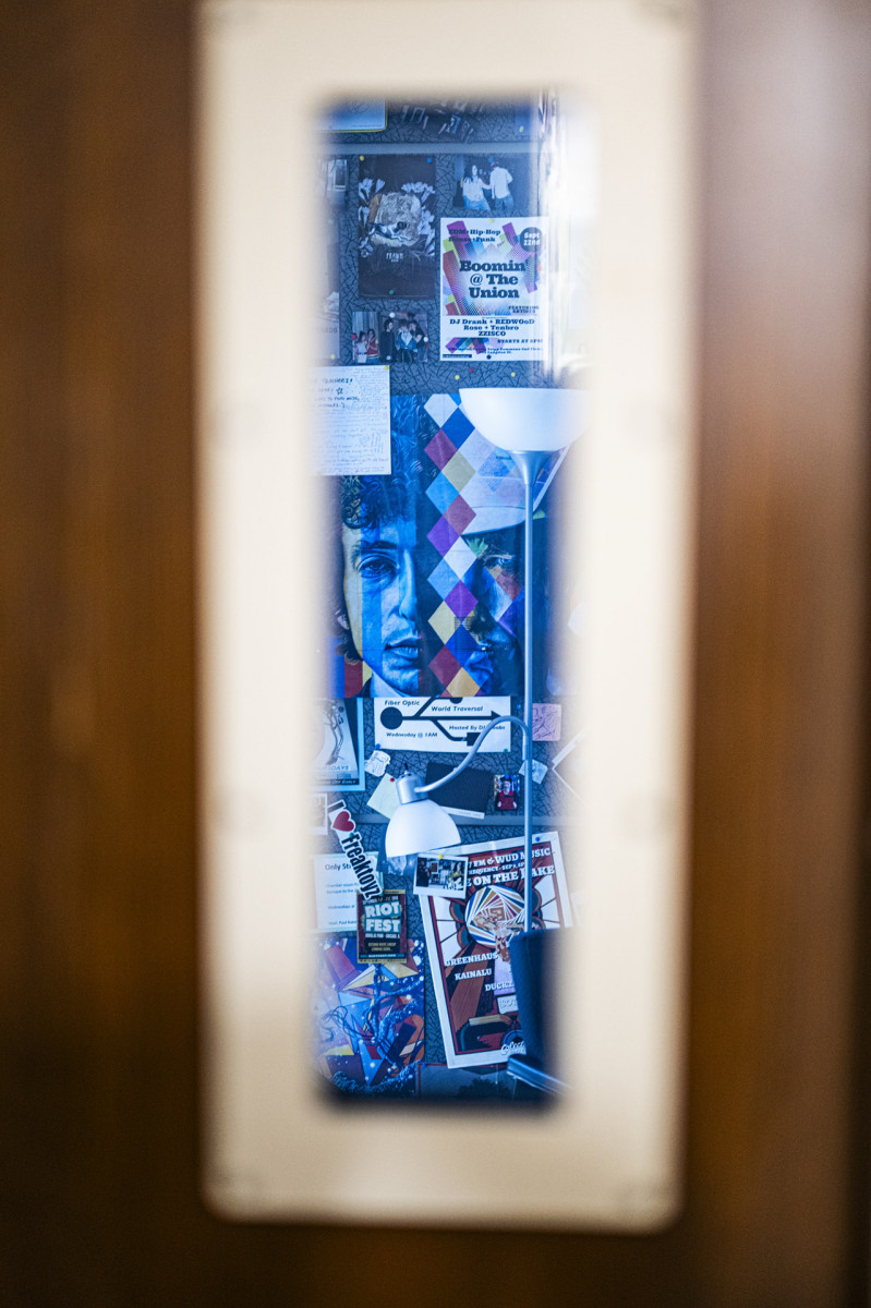 Posters in a broadcasting room are seen through a door at WSUM Radio