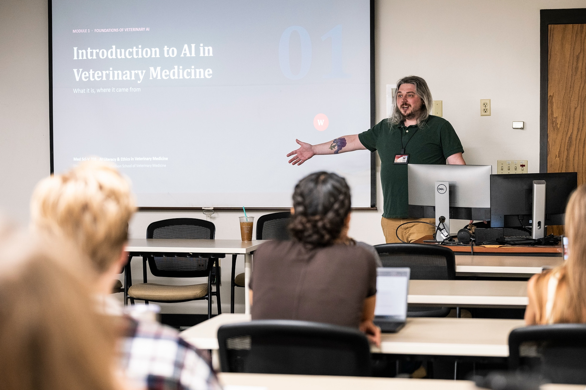 An instructor points to a screen in a classroom.