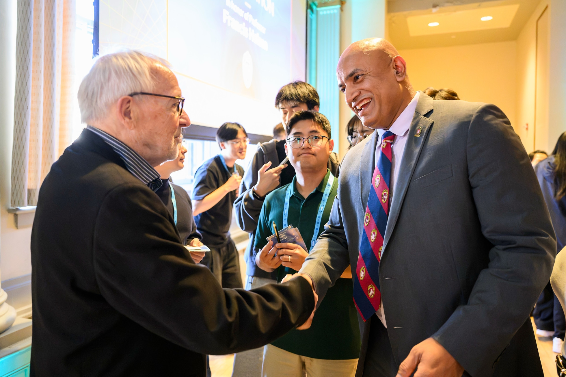 Nobel Laureate Francis Halzen shaking hands with the Dean of the College of Engineering Devesh Ranjan, while others wait to greet Halzen