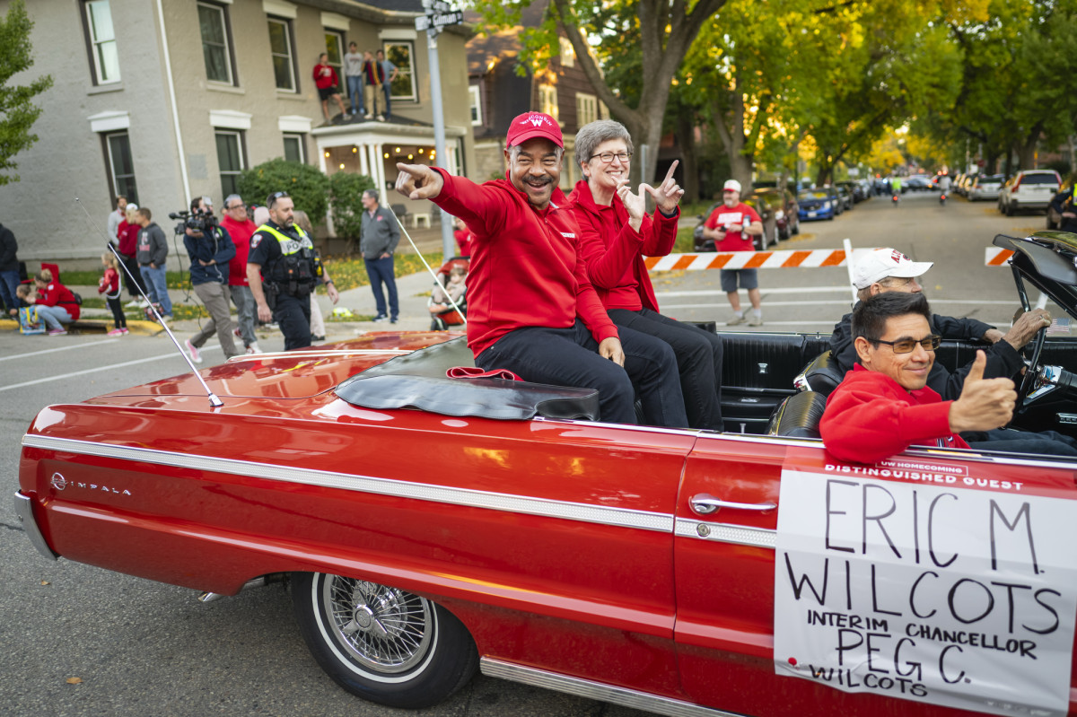 Interim Chancellor Eric Wilcots and his wife Peg Wilcots interact with the crowd from a red convertible during the UW Homecoming parade.