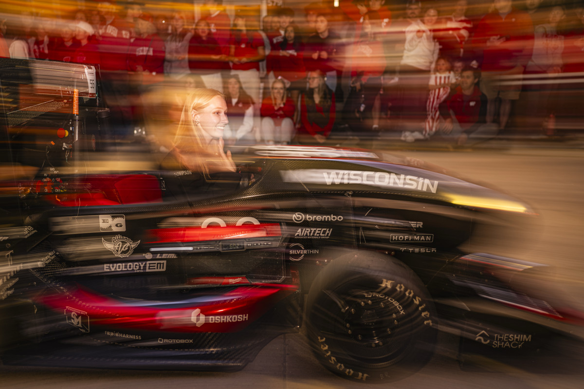 A young woman drives a hand-built race car down State Street.