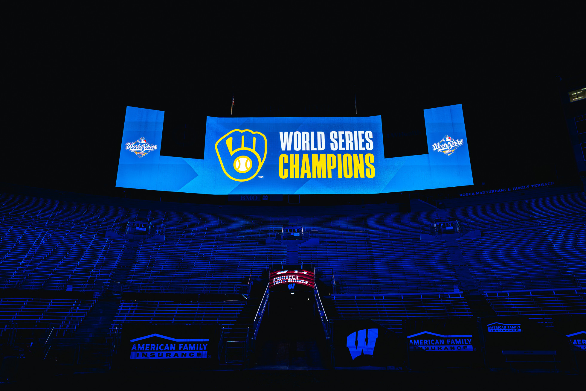 The scoreboard in a dimly lit Camp Randall stadium shows the Milwaukee Brewers logo with the words "World Series Champions."