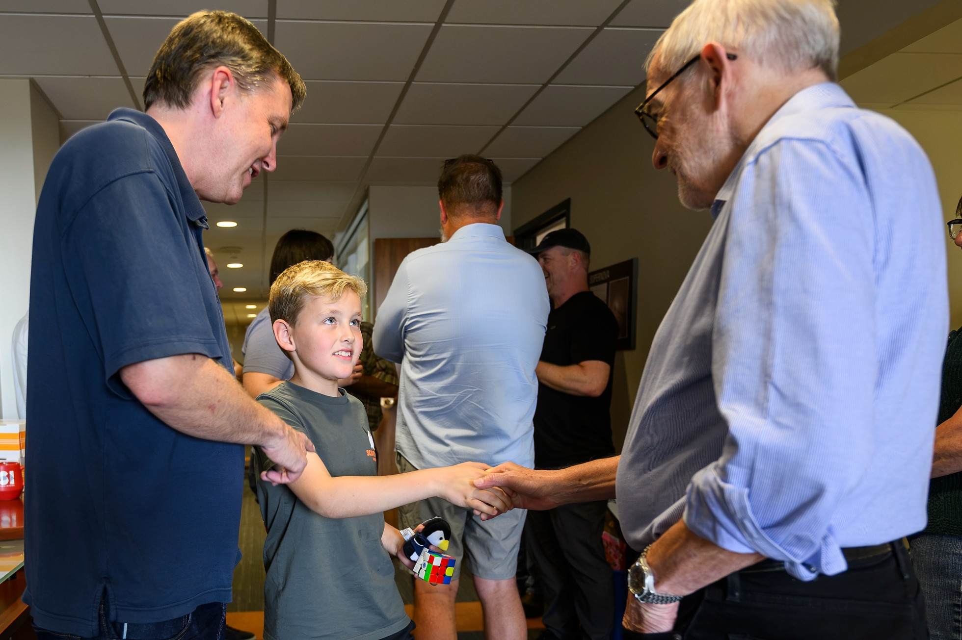 A 10-year-old boy, next to his father, shakes hands with Francis Halzen. 