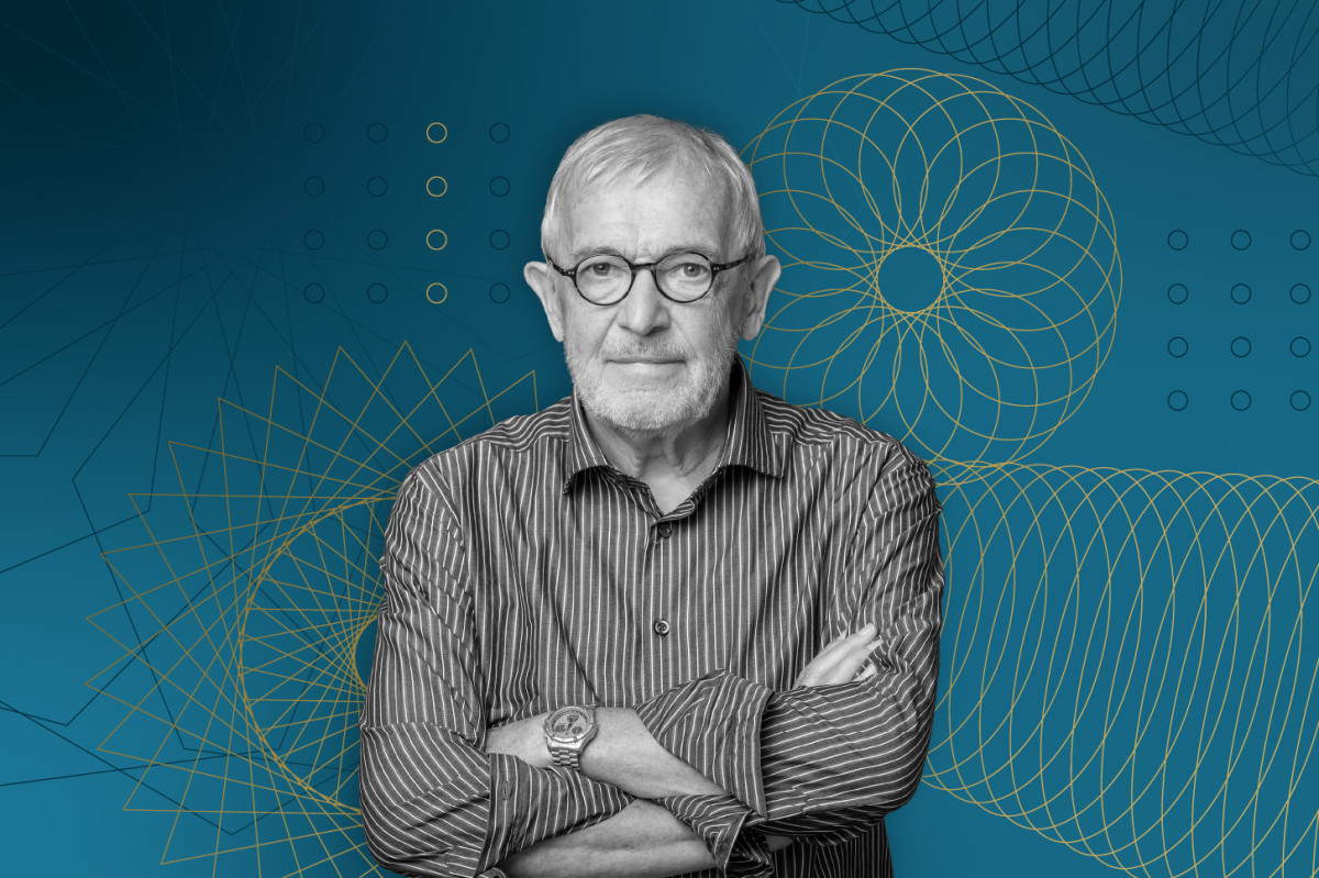 Portrait of UW–Madison physicist Francis Halzen wearing glasses and a striped button-down shirt with his arms crossed, set against a blue background with yellow geometric line art designs.
