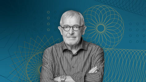 Portrait of UW–Madison physicist Francis Halzen wearing glasses and a striped button-down shirt with his arms crossed, set against a blue background with yellow geometric line art designs.